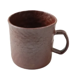 Plain white background front shot of rustic earthy ceramic coffee mug, clear display hand-pinched fingerprint texture, square handle and full floating red glaze surface