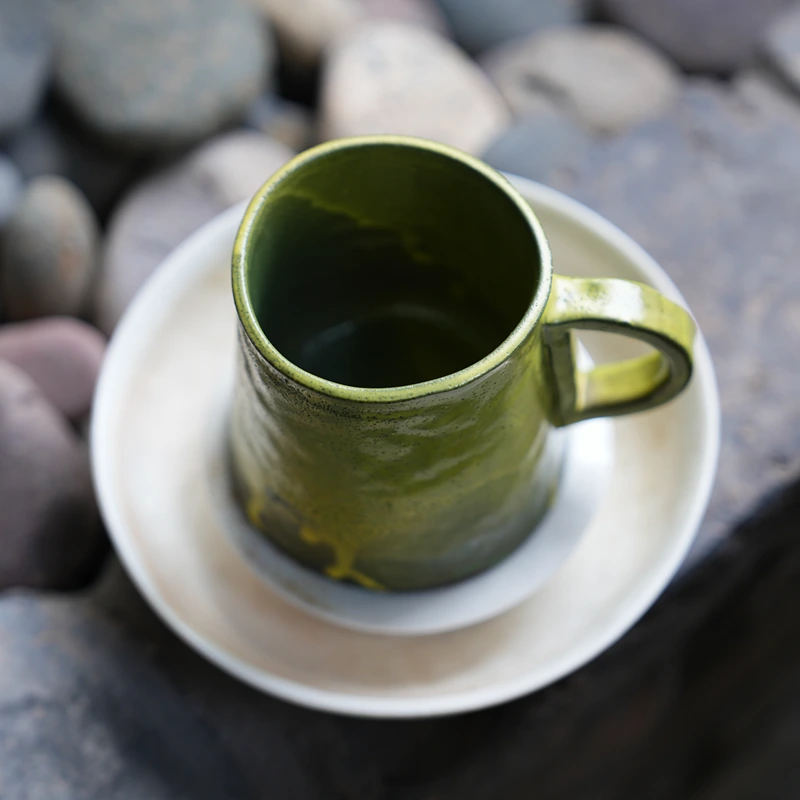 Handmade olive glaze ceramic mug displayed outdoors in a natural setting, inspired by slow living and forest landscapes